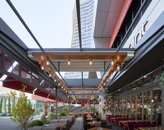alfresco dining restaurant covered witha pergola featuring an open retractable roof